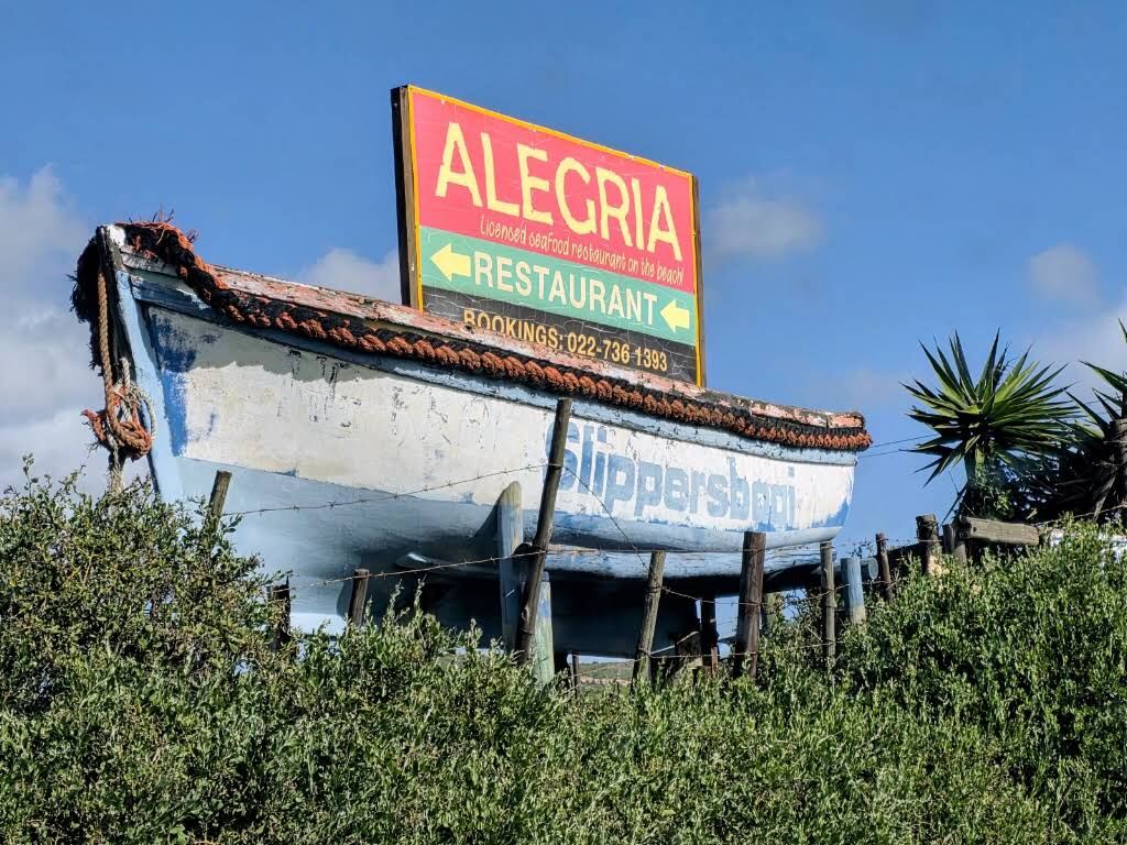 The Alegria sign mounted on an old fishing boat against a blue sky